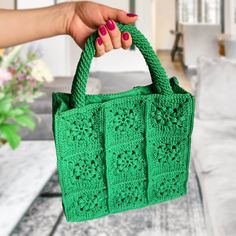 a hand holding a green crocheted purse