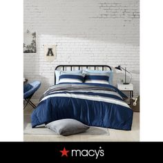 a bed room with a neatly made bed and a brick wall behind it that says macy's