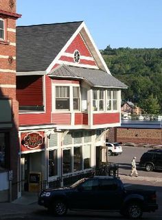 a car parked in front of a red building on the side of a road next to a parking lot