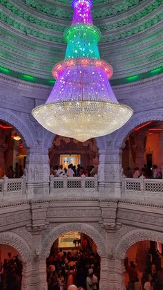 a large chandelier hanging from the ceiling in a building with people standing around it