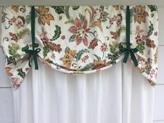 the curtain is hanging on the side of the window with green ribbon ties around it