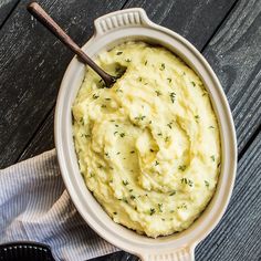 a bowl filled with mashed potatoes on top of a wooden table