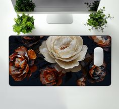 a computer monitor sitting on top of a desk next to a flower covered mouse pad