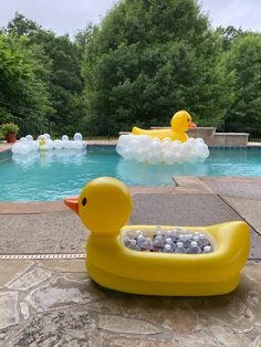 an inflatable rubber ducky sitting next to a swimming pool filled with rocks