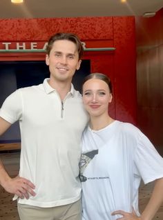 a man and woman posing for a photo in front of a red wall with the words theatre on it