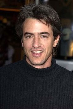 a close up of a person wearing a black sweater and posing for the camera with his hands in his pockets