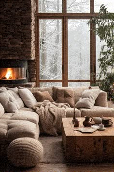 a living room filled with furniture and a fire place next to a large window on top of a wooden floor