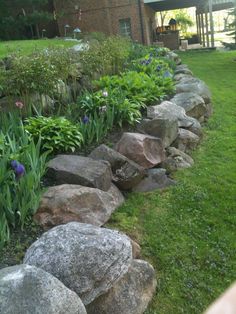 a garden with rocks and flowers in the grass