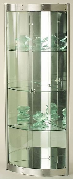 a curved glass display case with green dishes in the bottom section and two shelves on each side