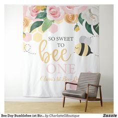 a wall hanging with a bee and flowers on it, next to a gray chair