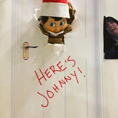 there's johnny from the elf movie peeking through a hole in the wall with his name on it