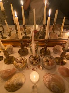 a table topped with lots of candles and seashells