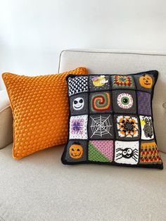 a white couch topped with a pillow covered in halloween themed crocheted squares and pumpkins