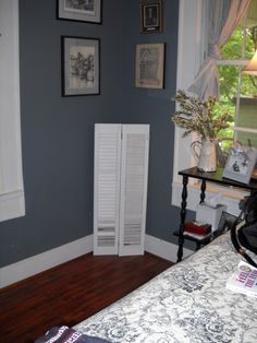 a bedroom with blue walls and white shutters