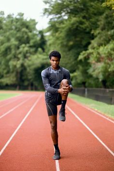 a young man running on a track with headphones in his ears and holding a football