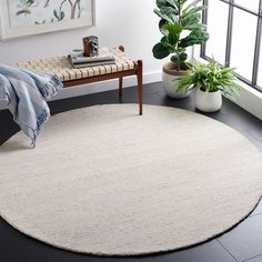 a large round rug in the corner of a room next to a window with potted plants