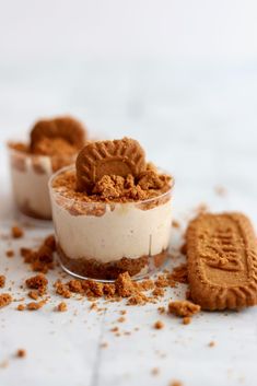 three desserts with cookies on the side and one cookie in the middle, sitting on a table