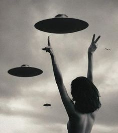 a woman is throwing frisbees in the air on an overcast day