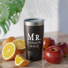 there is an apple and oranges on the table next to a tumbler cup