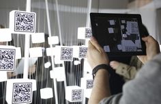 a person holding up a tablet with qr - code on the screen in front of them