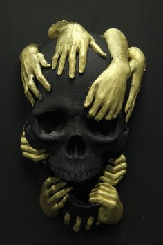 a gold and black skull with hands on it