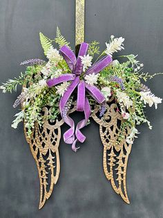 an angel wreath with purple ribbon hanging on a wall