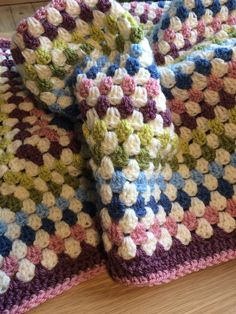 a multicolored crocheted blanket laying on top of a wooden floor