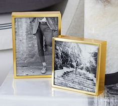 two black and white photos sitting on top of a table next to a vase with flowers