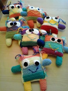 several crocheted stuffed animals are arranged on a wooden table, with eyes and nose