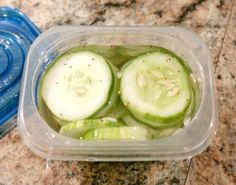 sliced cucumbers in a plastic container on a marble counter top with blue lids