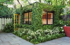 a house made out of plants and flowers in a backyard with a potted planter