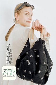 a woman is holding a black bag with white flowers on it and she has sunglasses on her head