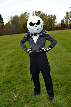 a man in a suit with a jack skellingy face on his head is standing in the grass