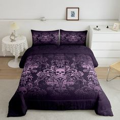 a bed with purple comforter and pillows in a room next to a white chair