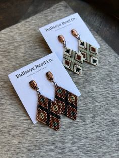 two pairs of beaded earrings sitting on top of a table next to each other