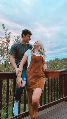 a man and woman standing on top of a wooden deck next to eachother