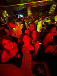 a group of people standing in front of a crowd at a party with red lights