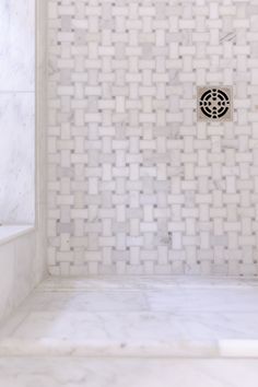 a white tiled shower with a drain in the middle