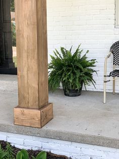 a chair and potted plant sitting on the front porch next to a white brick building