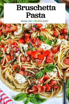 pasta with tomatoes, basil and mozzarella on a white plate next to silverware