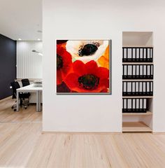 an abstract painting hangs on the wall next to a white table and bookshelf