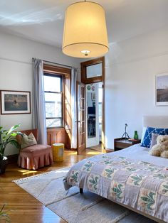 a bedroom with white walls and wooden flooring has a teddy bear on the bed