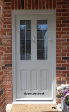 a white double door with two panes of glass on the side of a brick building