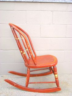 an orange rocking chair against a white brick wall