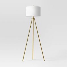 a gold tripod floor lamp with a white shade on the top and bottom part