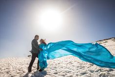 a man and woman are standing in the snow with a blue scarf around their neck