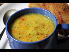 a blue bowl filled with soup on top of a white plate next to a slice of bread