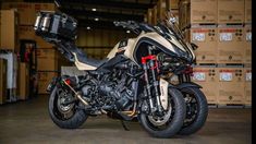 a motorcycle is parked in a warehouse with boxes on the floor and behind it are two motorcycles