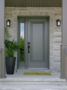 a gray front door with two planters on either side