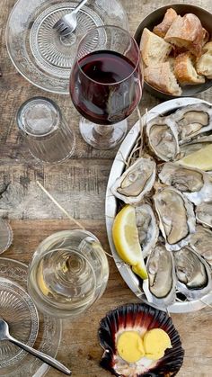 oysters on the half shell with bread, wine and glass of red wine sitting on a wooden table